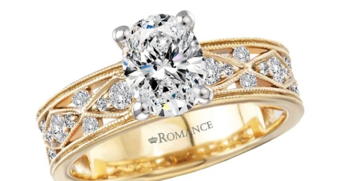 A gold ring has a large oval-cut center diamond. Smaller round diamonds are set along an open, crisscross-style band.